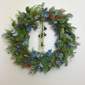 Christmas wreaths with seasonal foliage, cones, orange and cinnamon tied with a handmade bow