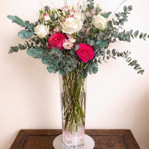 Tall vase arrangement with white and pink Ecuadorian roses, lisianthus, eucalyptus and festive additions