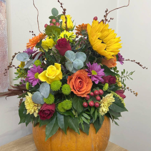 Floral pumpkin arrangement using seasonal flowers and foliage. Roses, Gerbera, Sunflowers, Thistle, Hypericum, Crysanthemum. Eucalyptus, and Ivy