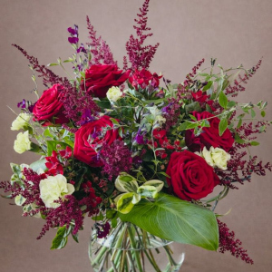 flower arrangement in glass vase with red and cream roses