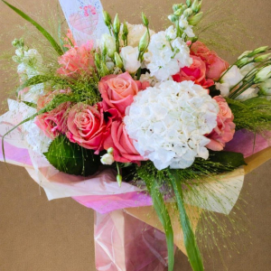 large bouquet of pink roses surrounded with white flowers in pink bag
