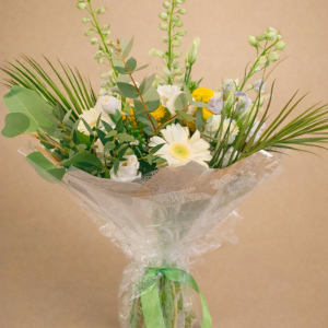 spray of white and yellow flowers with green foliage and green ribbon