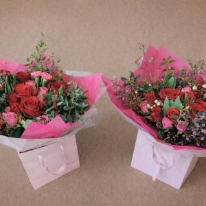 two bouquets of red and pink roses in pink bags