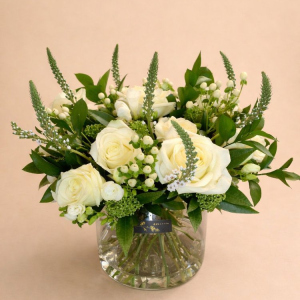 White roses, green foliage in a glass jug