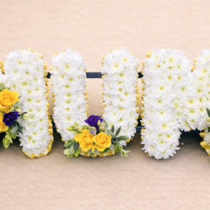 Yellow, white and purple tribute with a base of white chrysanthemum, yellow ribbon and sprays of yellow roses, foliage and lisianthus
