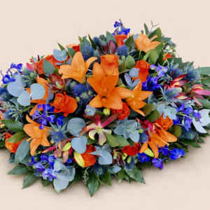 circular spray, orange, red and blue on bed of green foliage