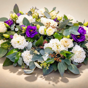 funeral wreath with white and violet flowers supported by green foliage