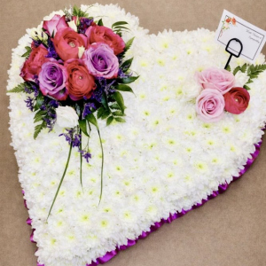heart shaped bed of white flowers with red and pink roses in corner