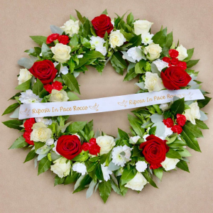 Wreath with red and white and yellow roses cradled in green foliage