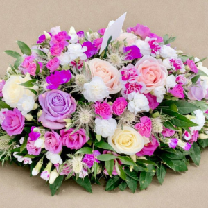 wreath with multicoloured flowers on bed of green foliage