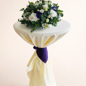 blue and white flower arrangement on stand covered with cream cloth