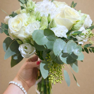 hand holding posy of white flowers with green foliage